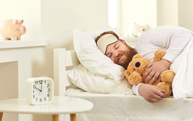 Mann schläft friedlich mit seinem Teddy Bär